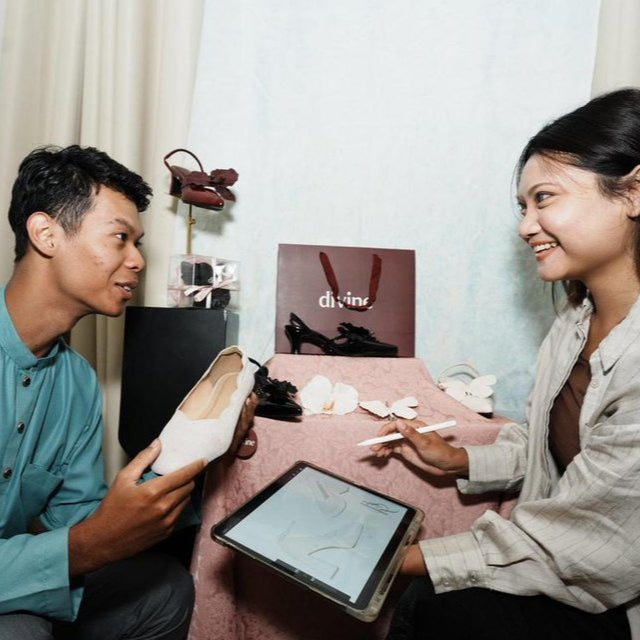 Two people sitting at a table with a tablet, discussing something.